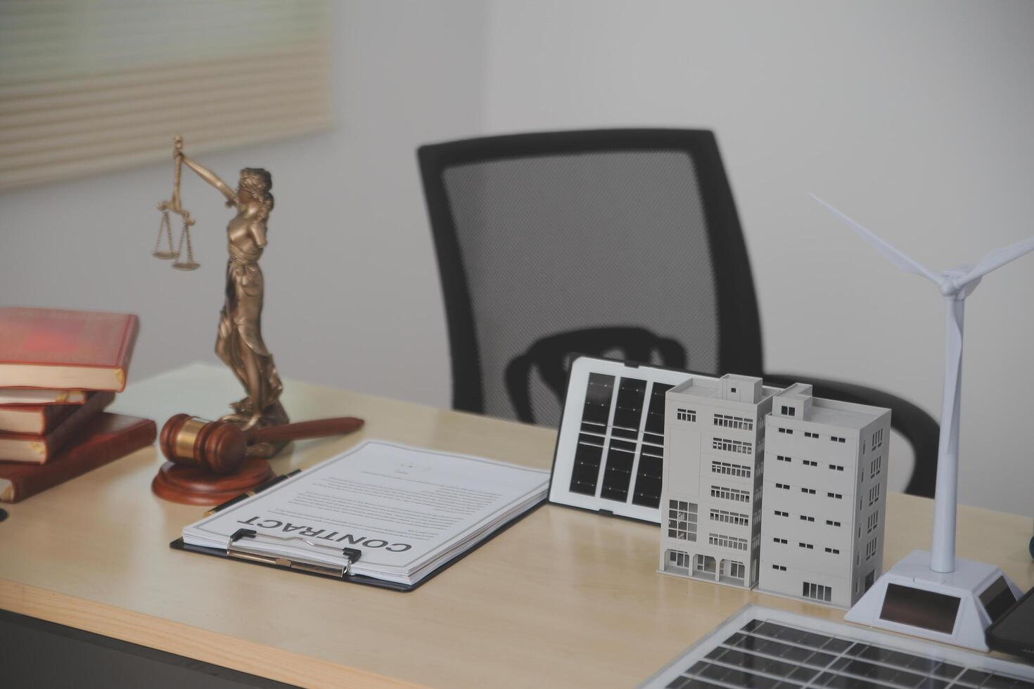 A desk with a statue of a judge, books, and a wind turbine photo