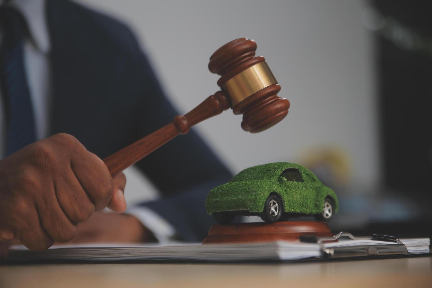 A judge's gavel is used to strike a car model on a desk photo