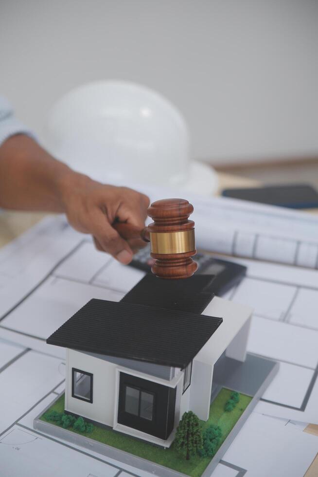 A person holding a gavel over a model of a house photo