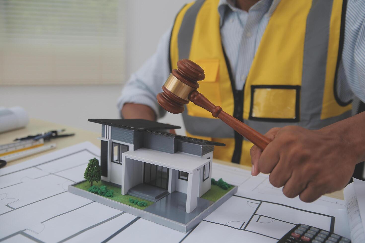 A man holding a gavel and looking at a model house photo