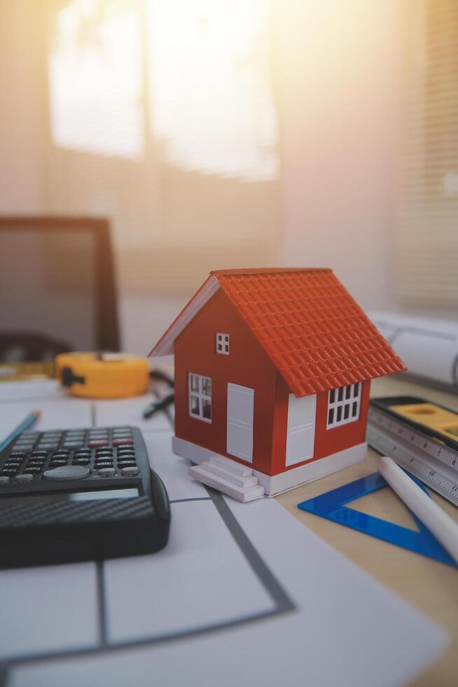 A house model sits on a desk with a calculator and a calculator photo
