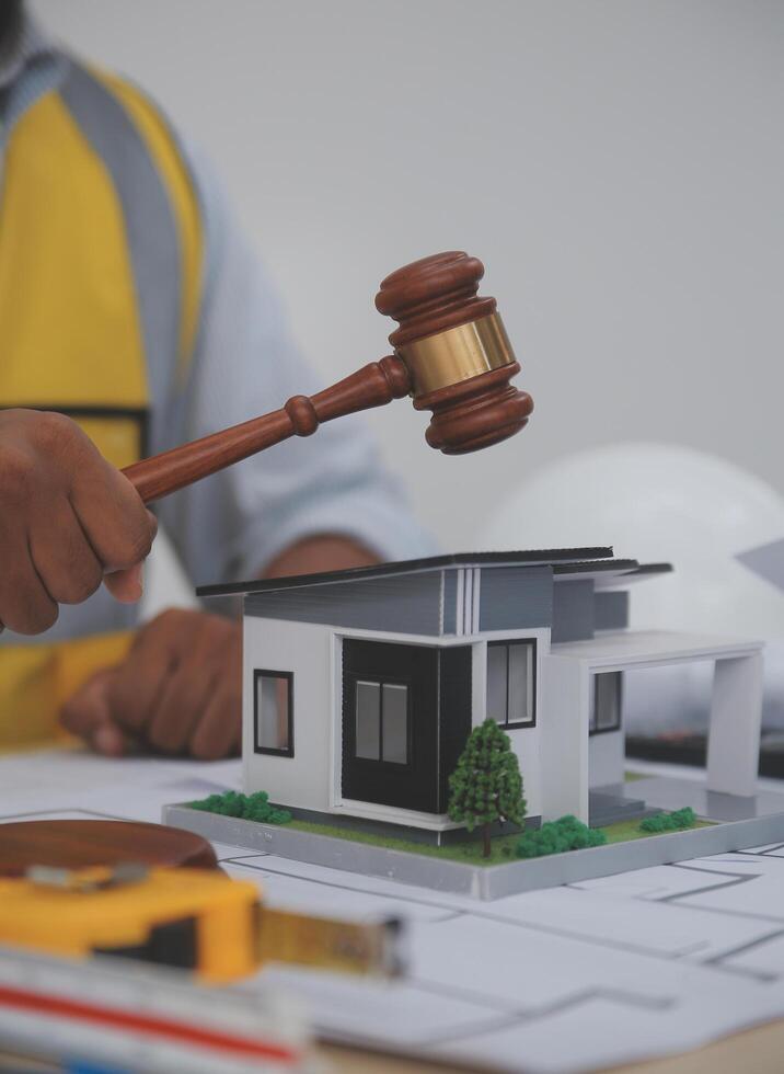 A man holding a gavel over a model of a house photo