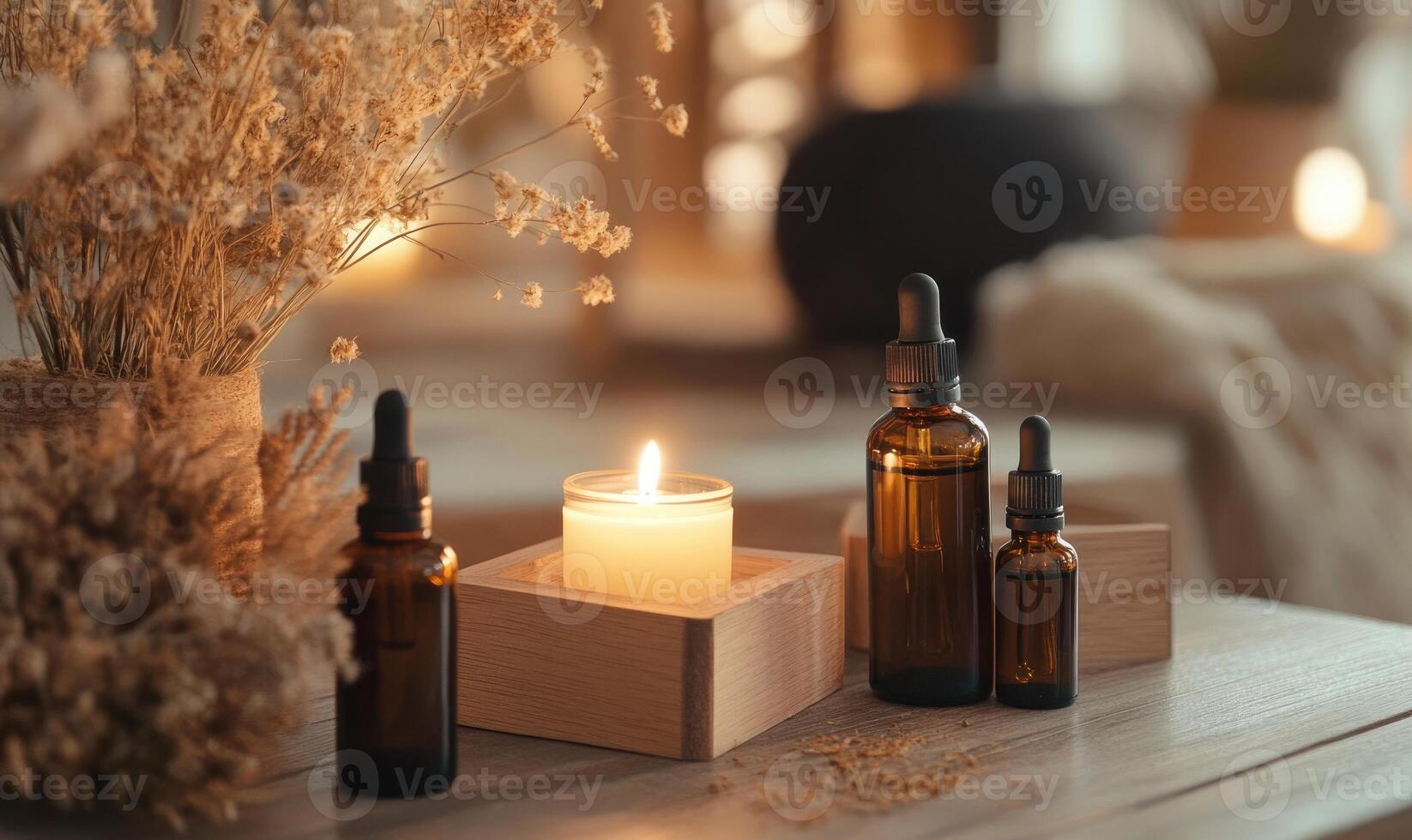 A candle is lit on a table with three bottles of essential oils photo