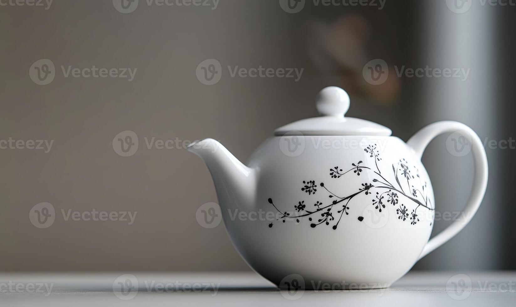 A white tea pot with a black flower design on it photo