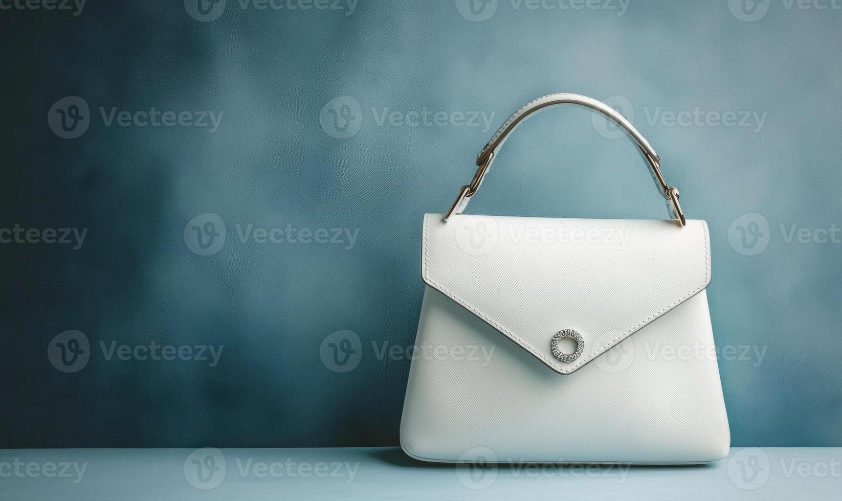 A white purse with a gold handle sits on a blue surface photo