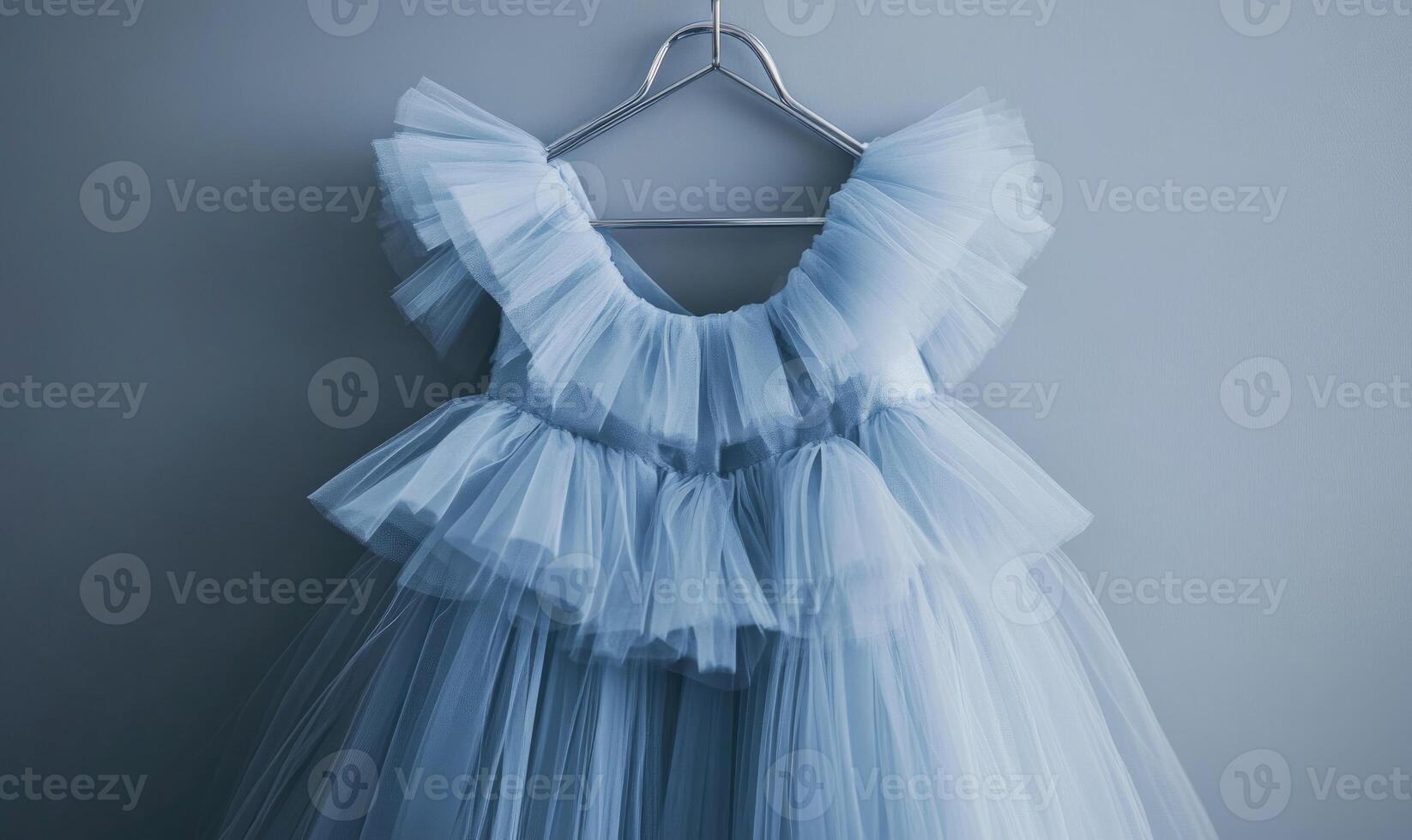 A blue dress with a ruffled collar is hanging on a hanger photo