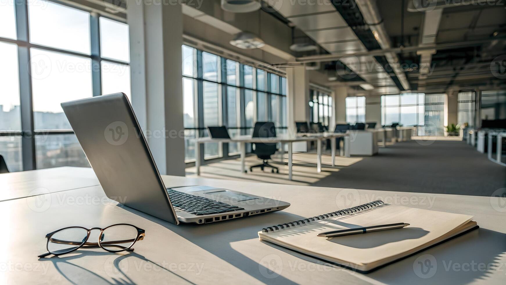 Sunlit Modern Office Desk with Laptop Notebook and Glasses photo