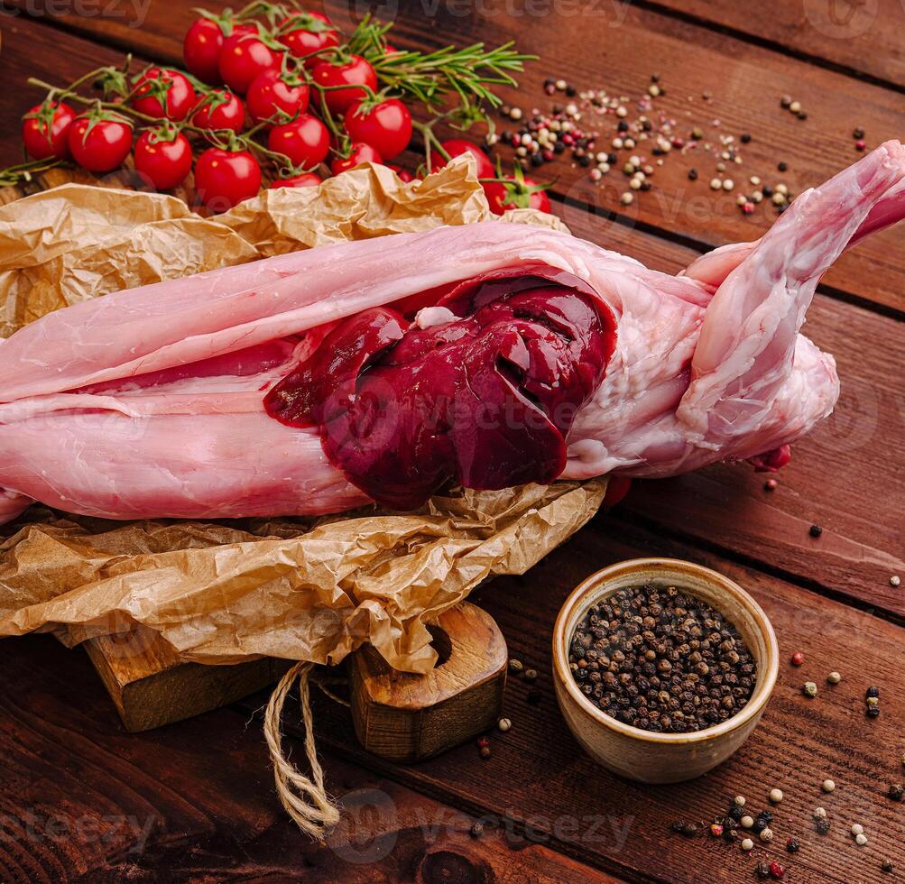 Fresh rabbit meat with herbs and cherry tomatoes on wooden table photo
