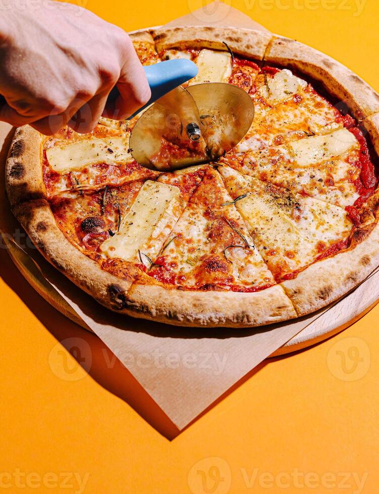 Slicing a fresh pizza with cheese and pineapple topping photo