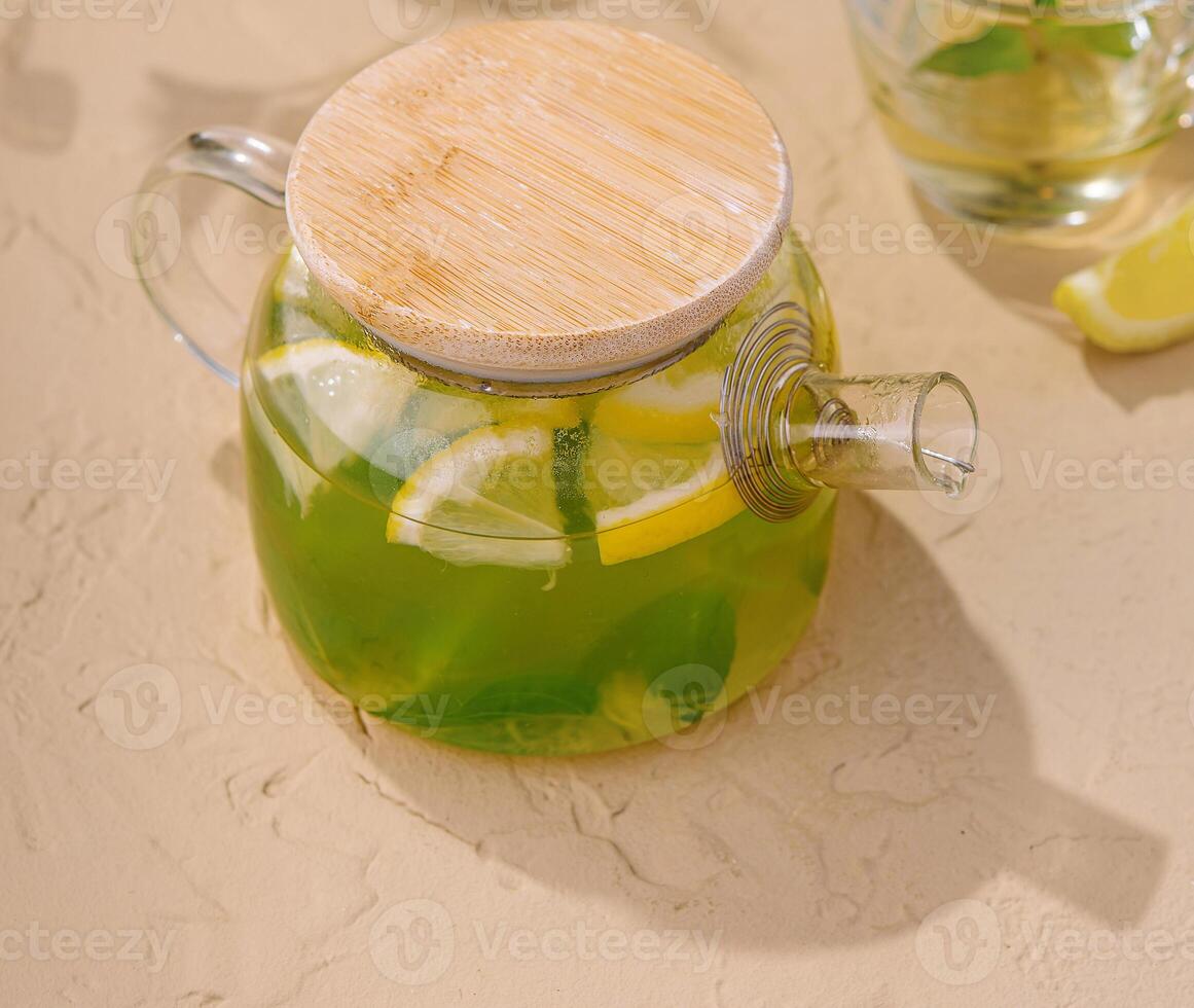 Fresh mint tea in glass teapot with lemon slices top view photo