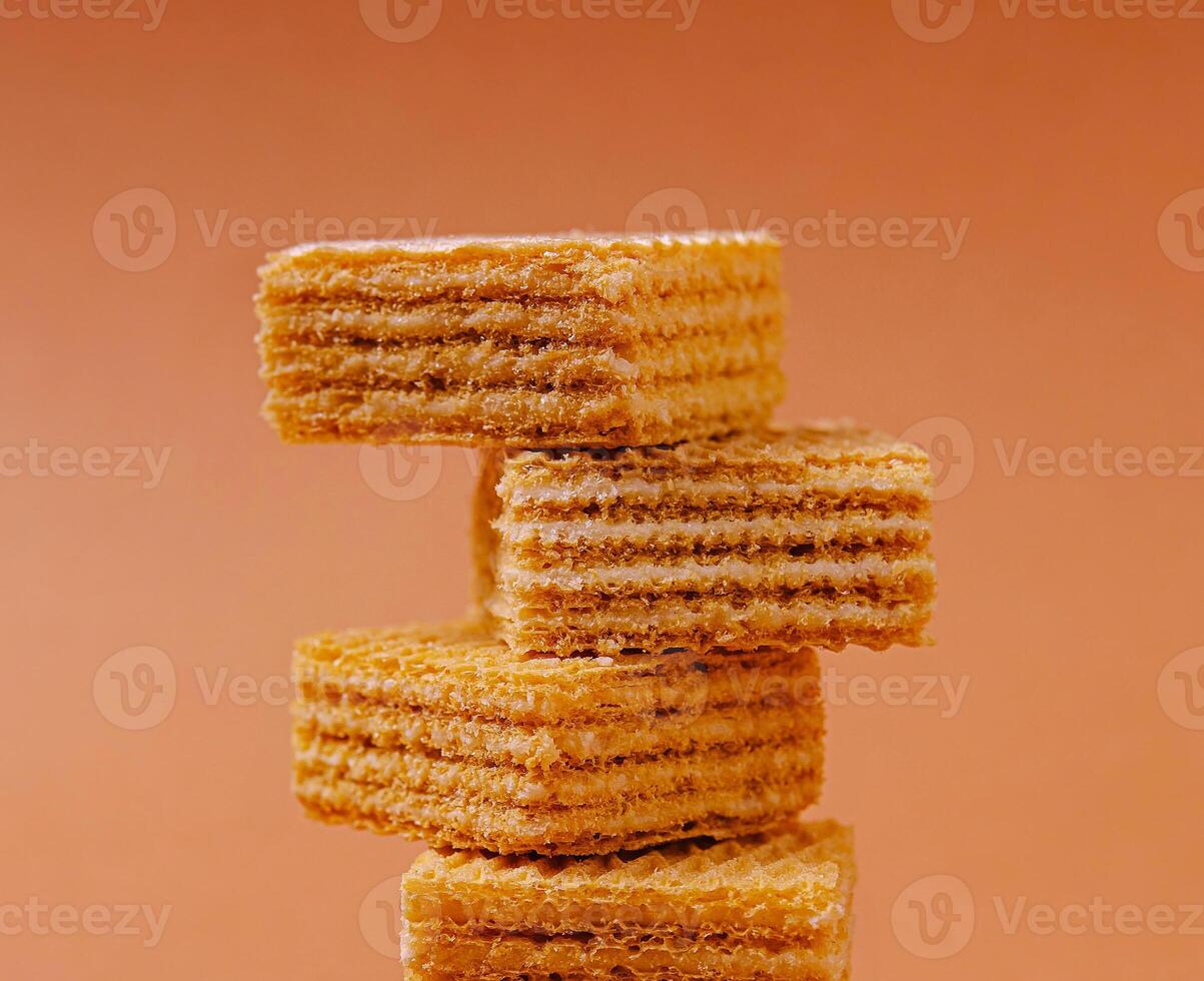 Layers of crispy wafers stacked against a soft orange background photo