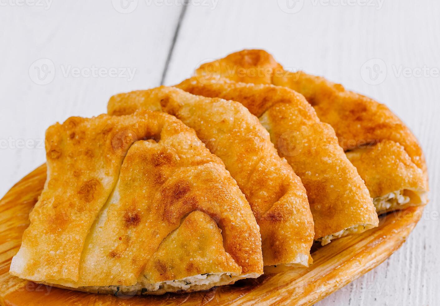 Delicious chebureki pastries resting on wooden plate photo