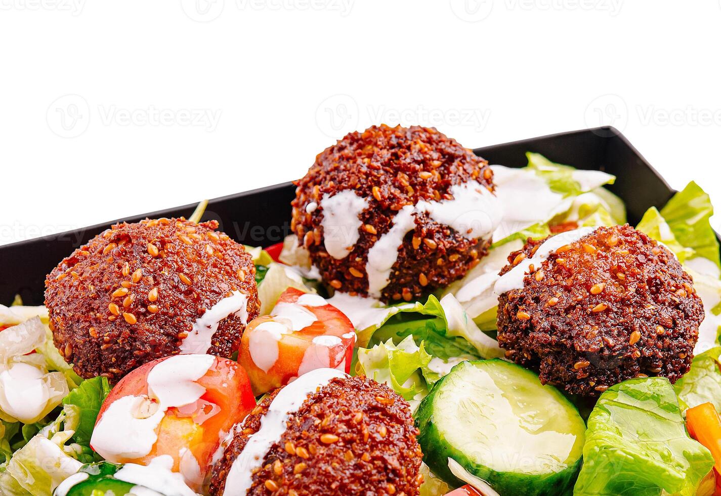 Fresh salad with crispy falafel and drizzled sauce served on plate photo