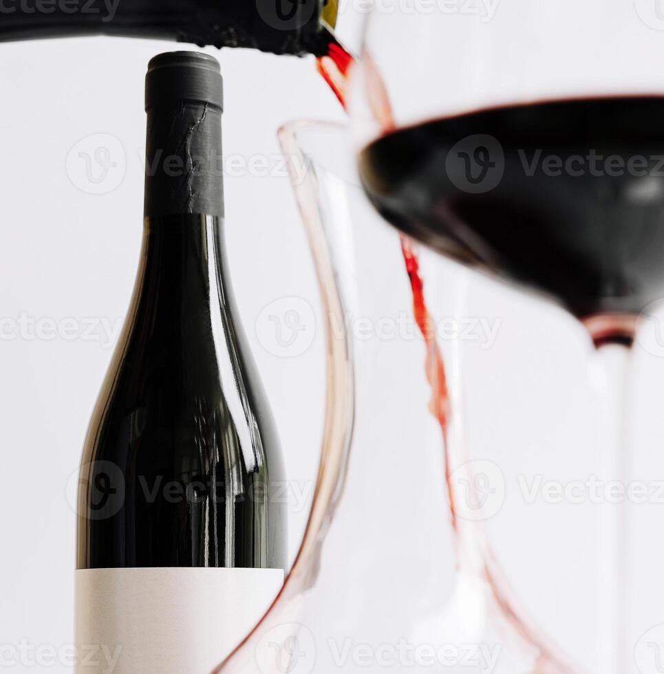 Pouring red wine into a glass near a bottle on a table photo