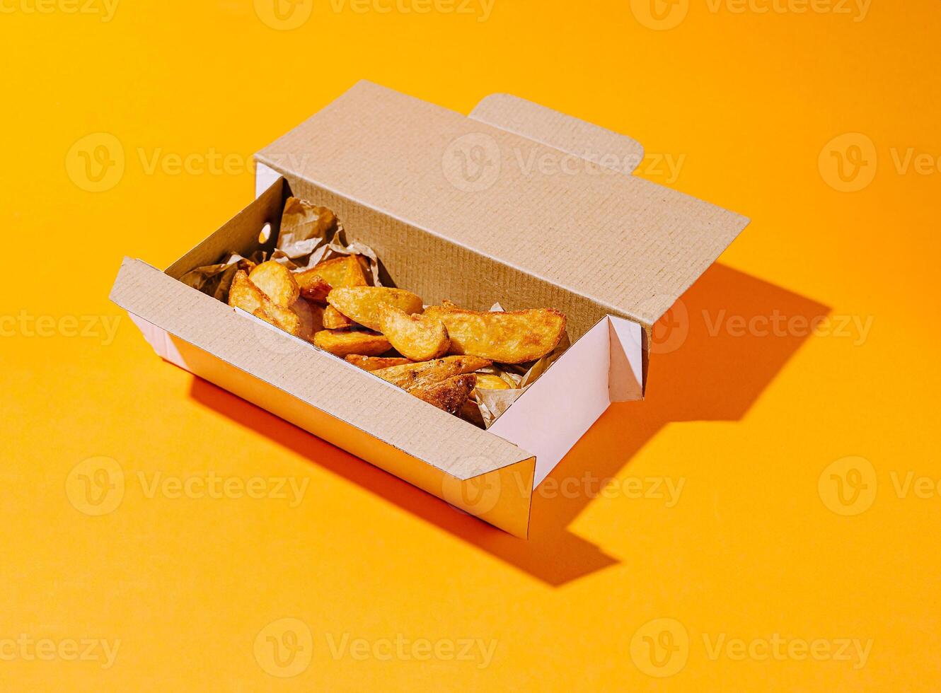 Crispy golden fries served in a cardboard box on bright background photo
