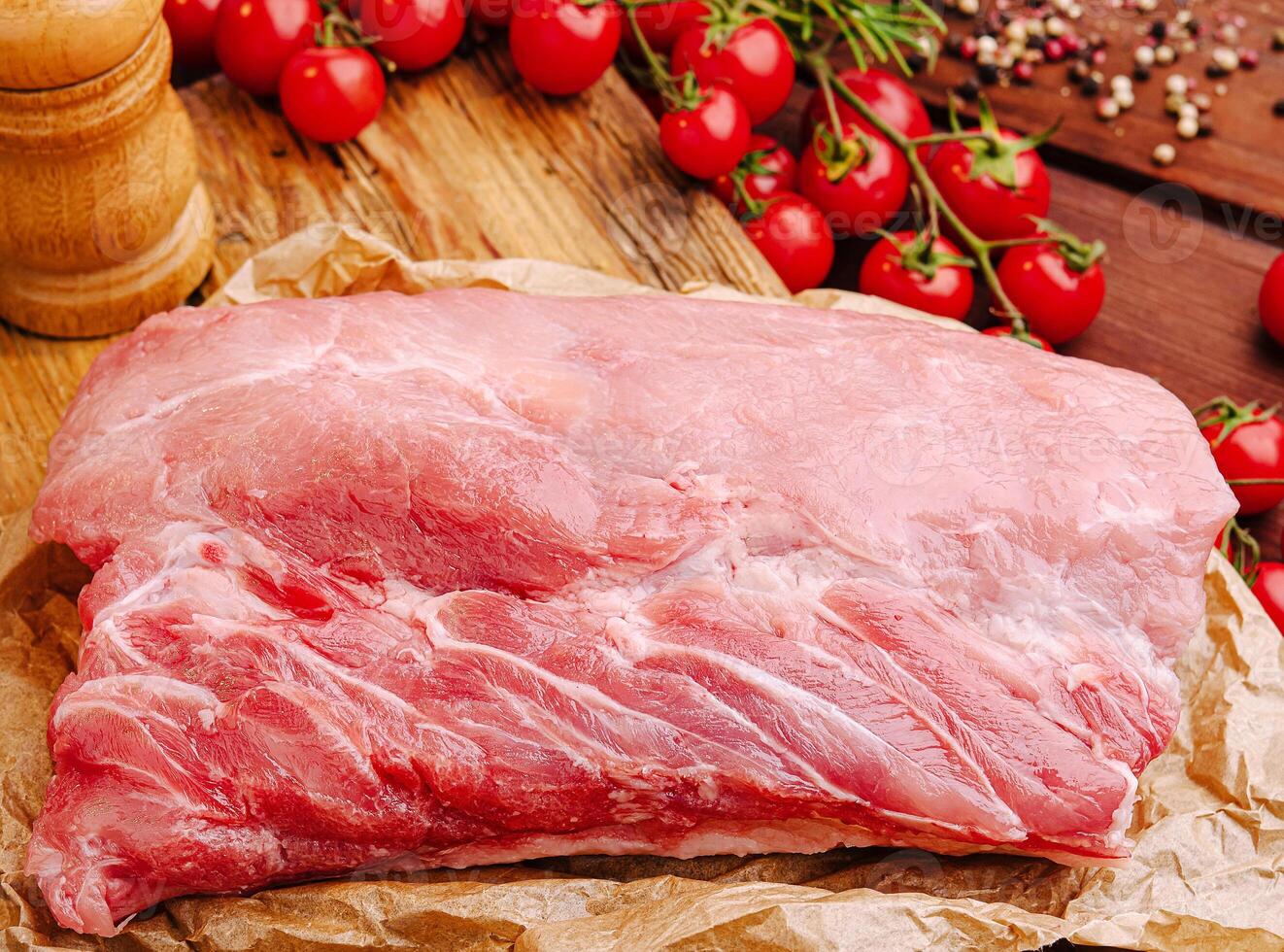 Fresh cut of pork with tomatoes and spices on wooden board photo