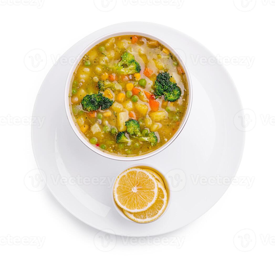 Warm vegetable soup served with lemon slices on a white plate photo