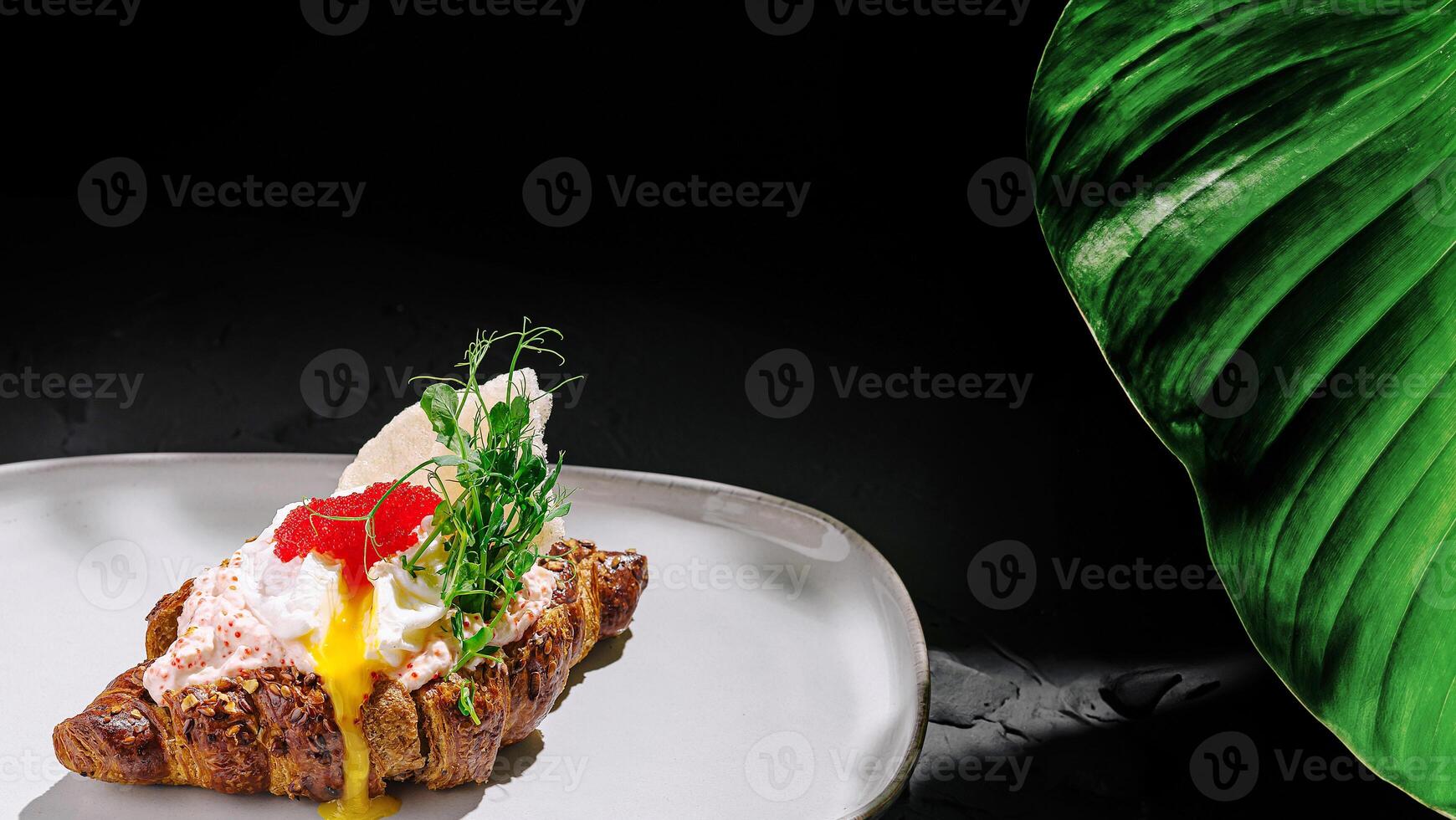 Delicious croissant topped with soft egg and fresh herbs on a plate photo