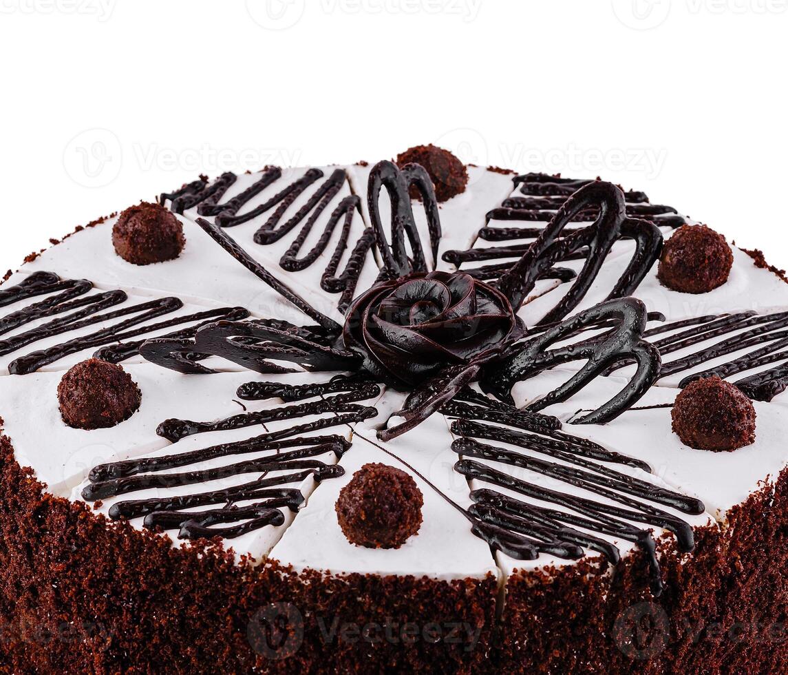 Chocolate cake with white icing being decorated with chocolate sauce photo