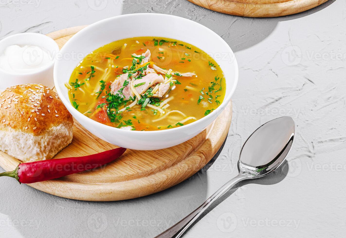 Delicious chicken noodle soup served with fresh bread and chili photo