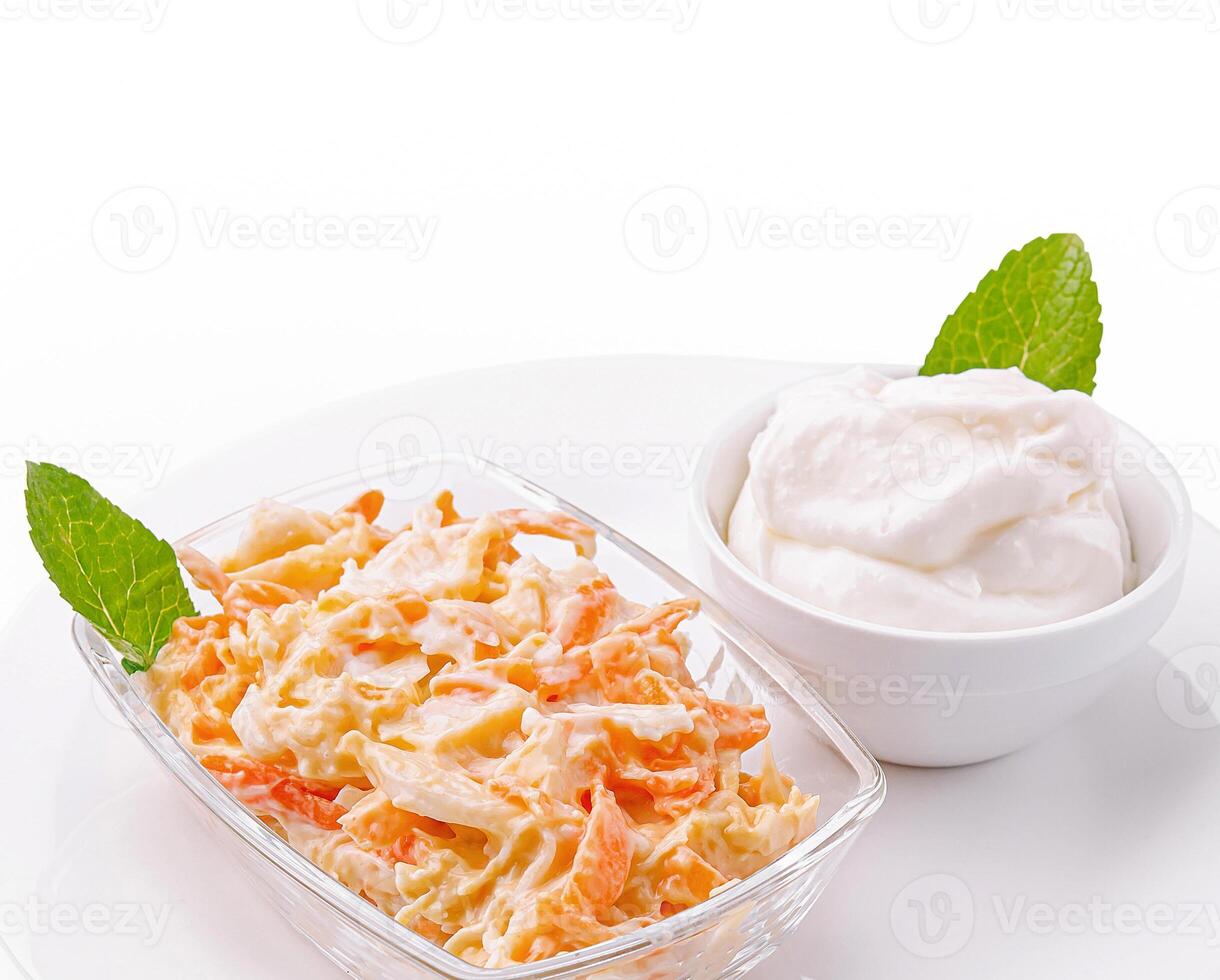 Creamy coleslaw with a side of yogurt served in a clear dish photo