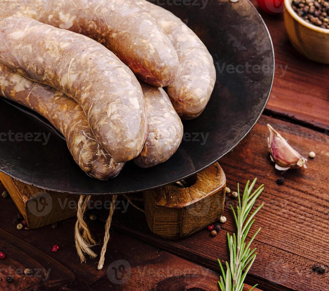 Juicy sausages on cast iron skillet with fresh herbs and spices photo