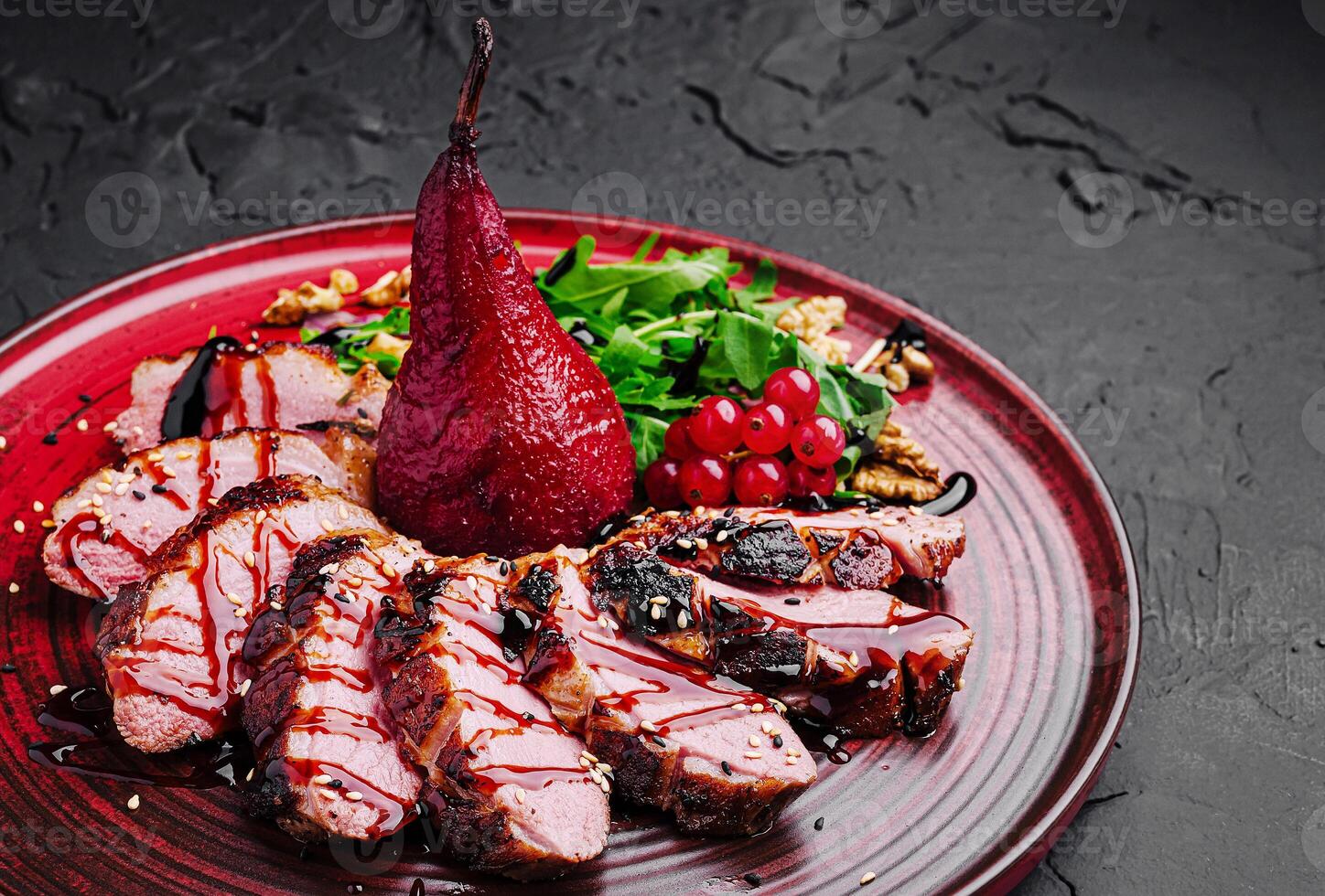 Gourmet duck breast with poached pear and salad on a decorative plate photo