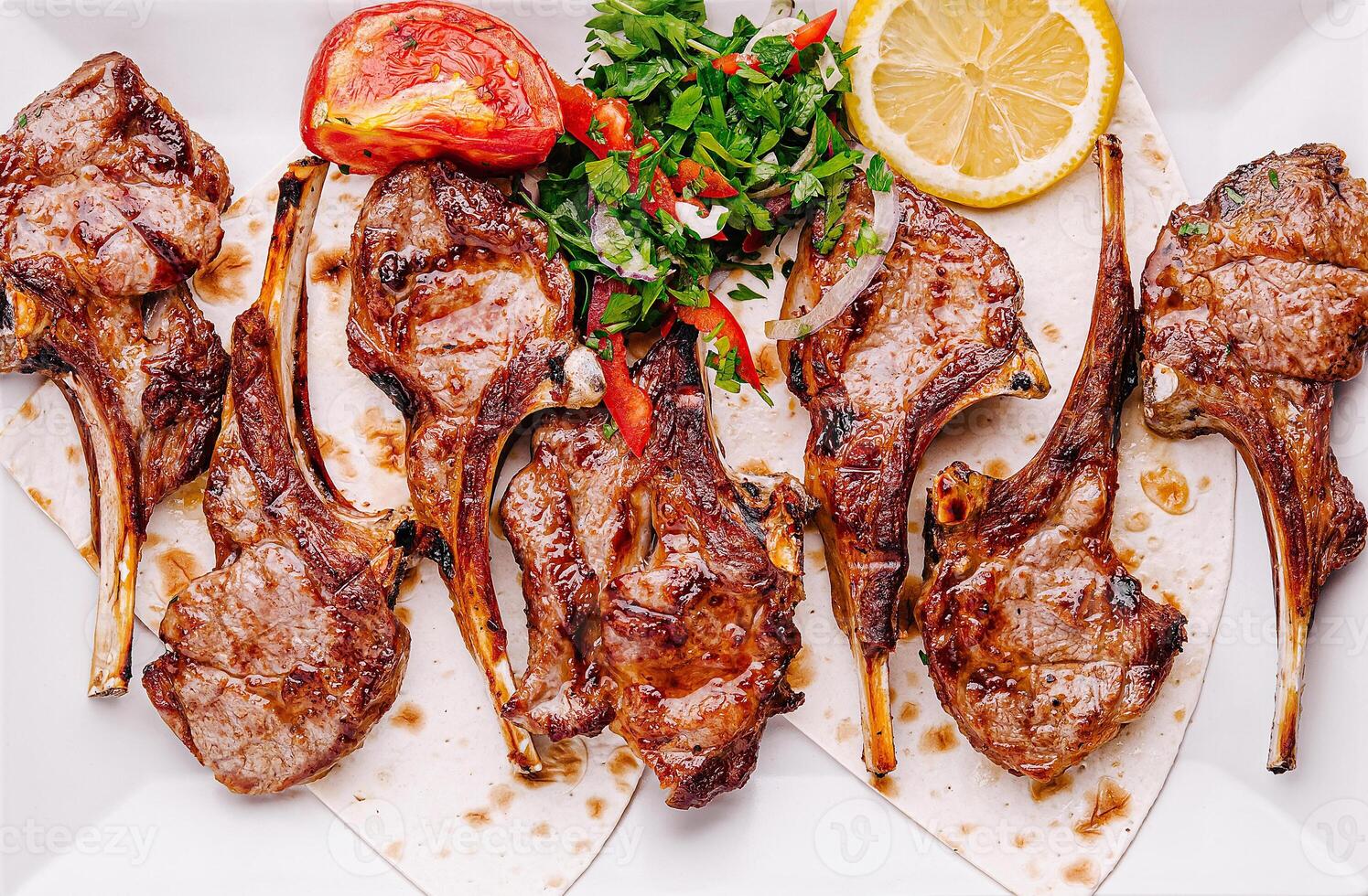 Delicious grilled lamb chops served with fresh garnish and lemon photo