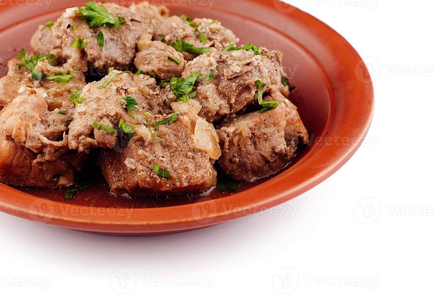 Stewed pork meat with herbs and spices on a plate closeup photo