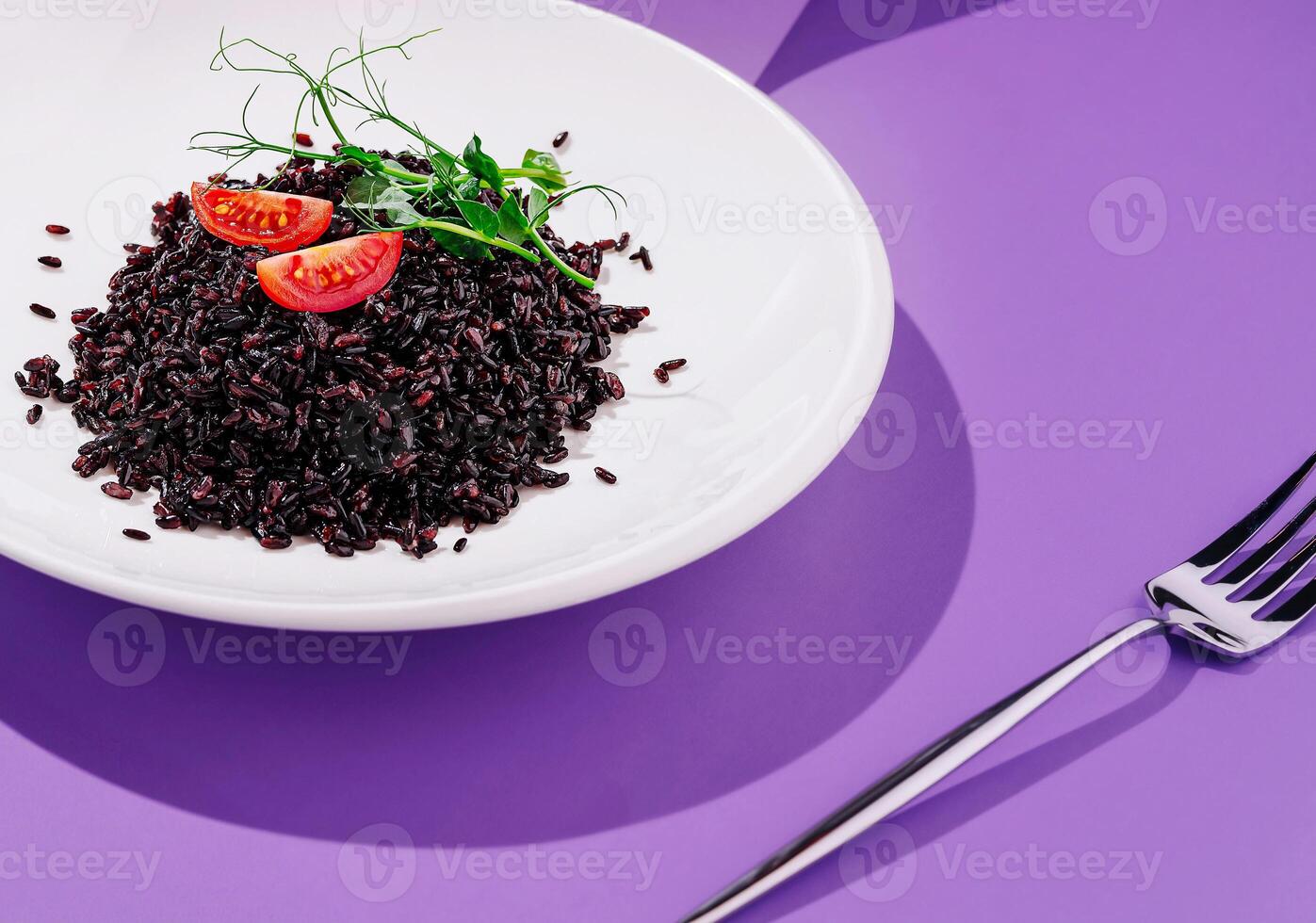 Delicious black rice dish garnished with fresh tomatoes and herbs photo