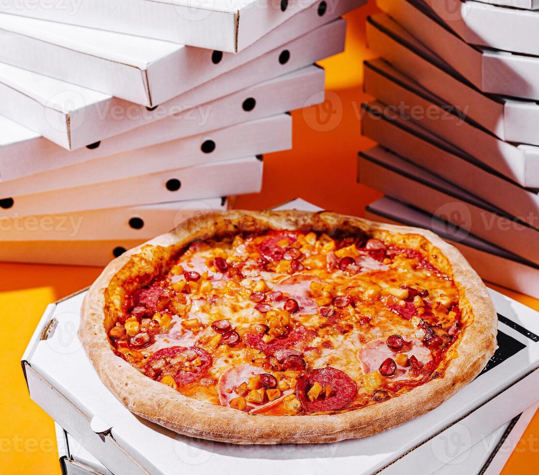 Delicious pizza on a bright orange background with pizza boxes photo