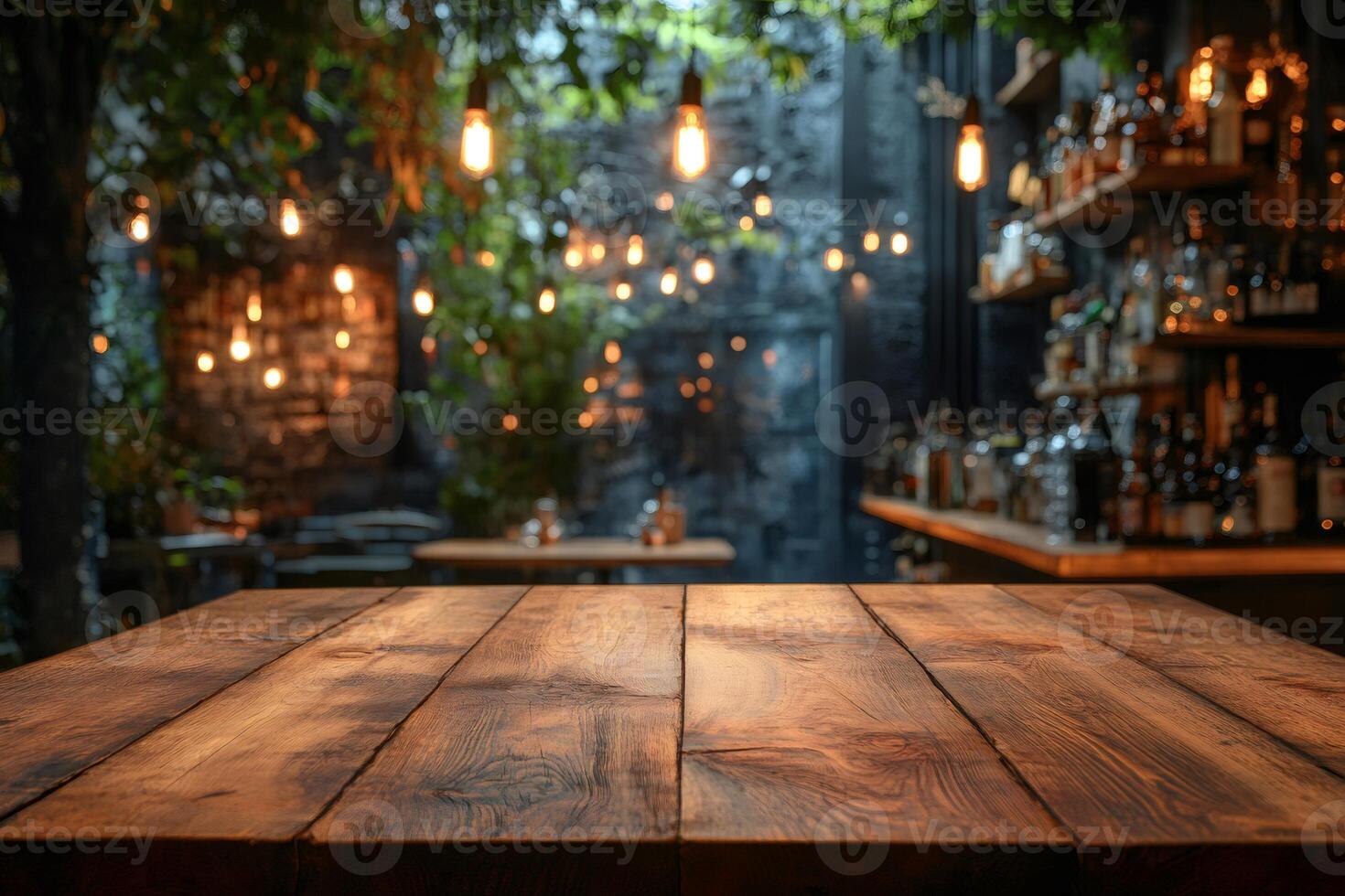 Empty wooden table in front of blurred cafe background with hanging light bulbs photo