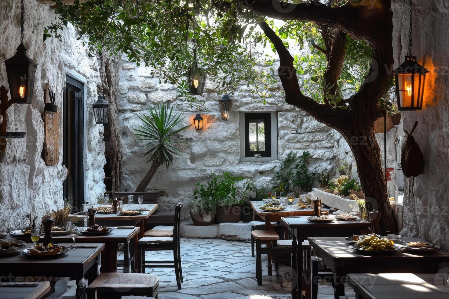 Charming restaurant tables set outdoors under a tree in a stone courtyard photo