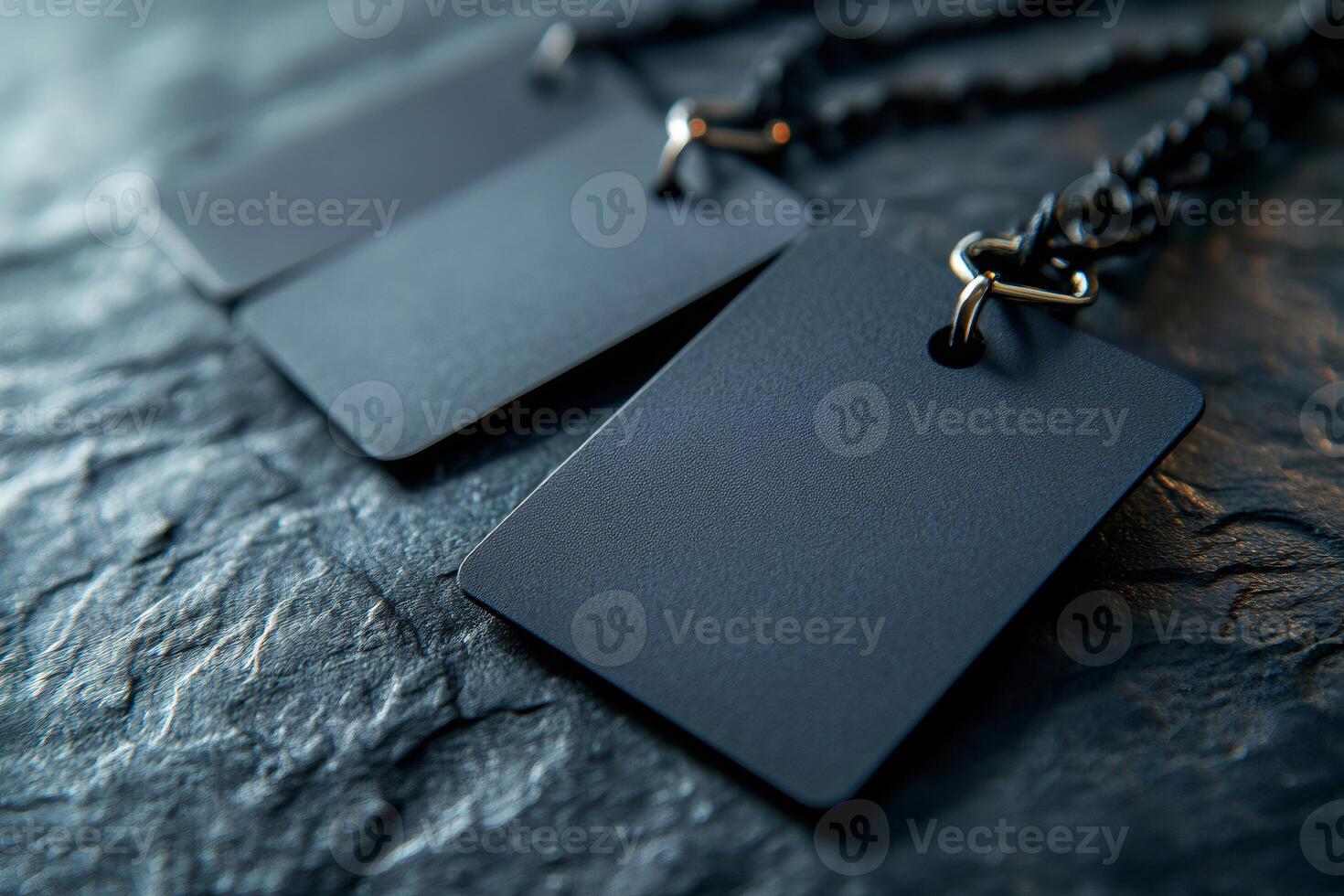Blank black square tags hanging on a chain on dark stone background photo