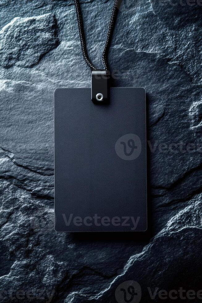Blank black identification card hanging on black lanyard on dark stone background photo