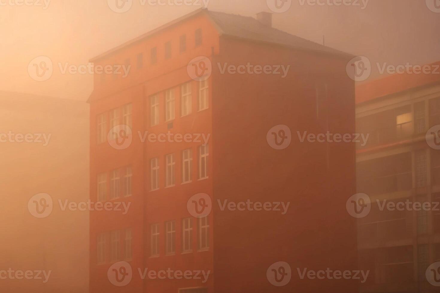A building is seen in the fog in front of a building photo
