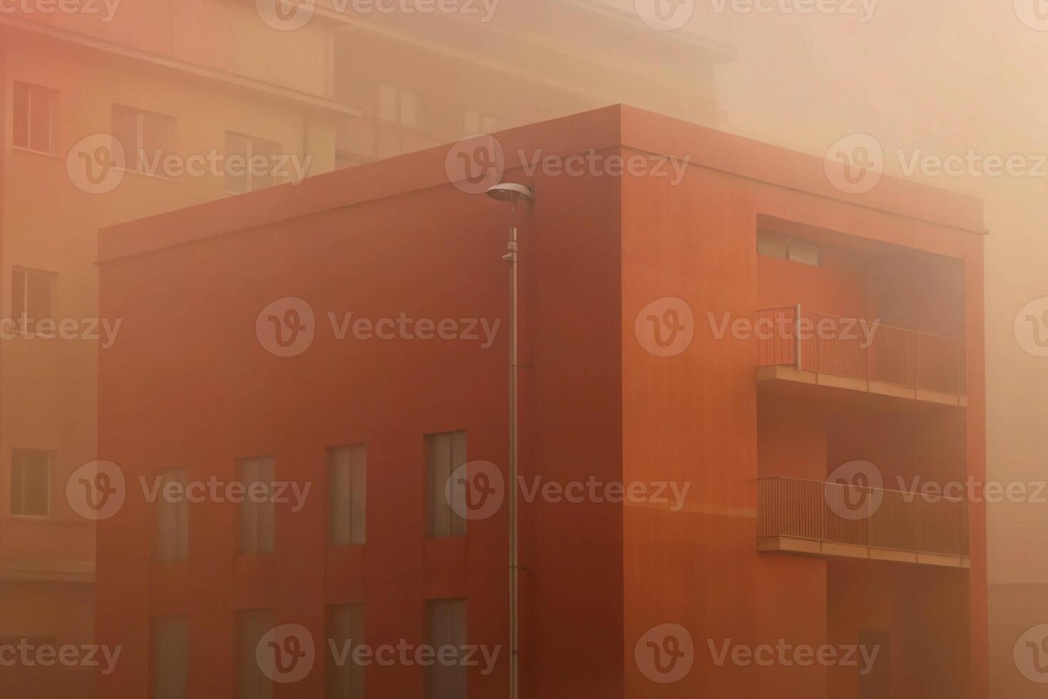 A hazy orange building on a foggy day with a neighboring building visible photo