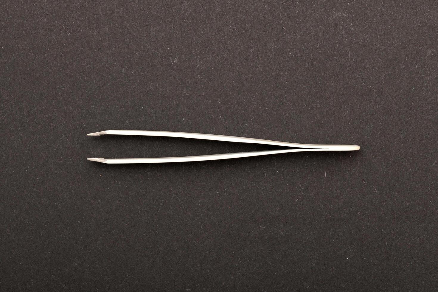 Top view extreme macro photography of white metal tweezers isolated on black background photo