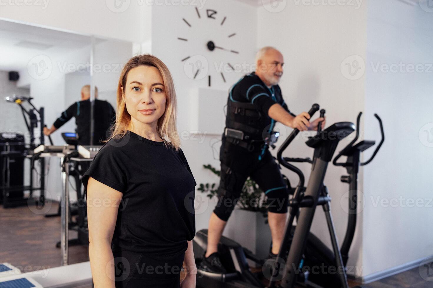 Personal female trainer with her client in ems suit in gym. photo