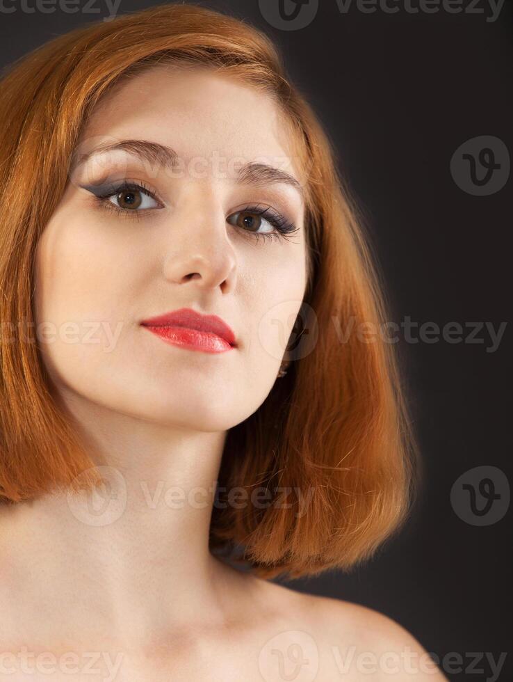 Beautiful young woman with red hair on black photo