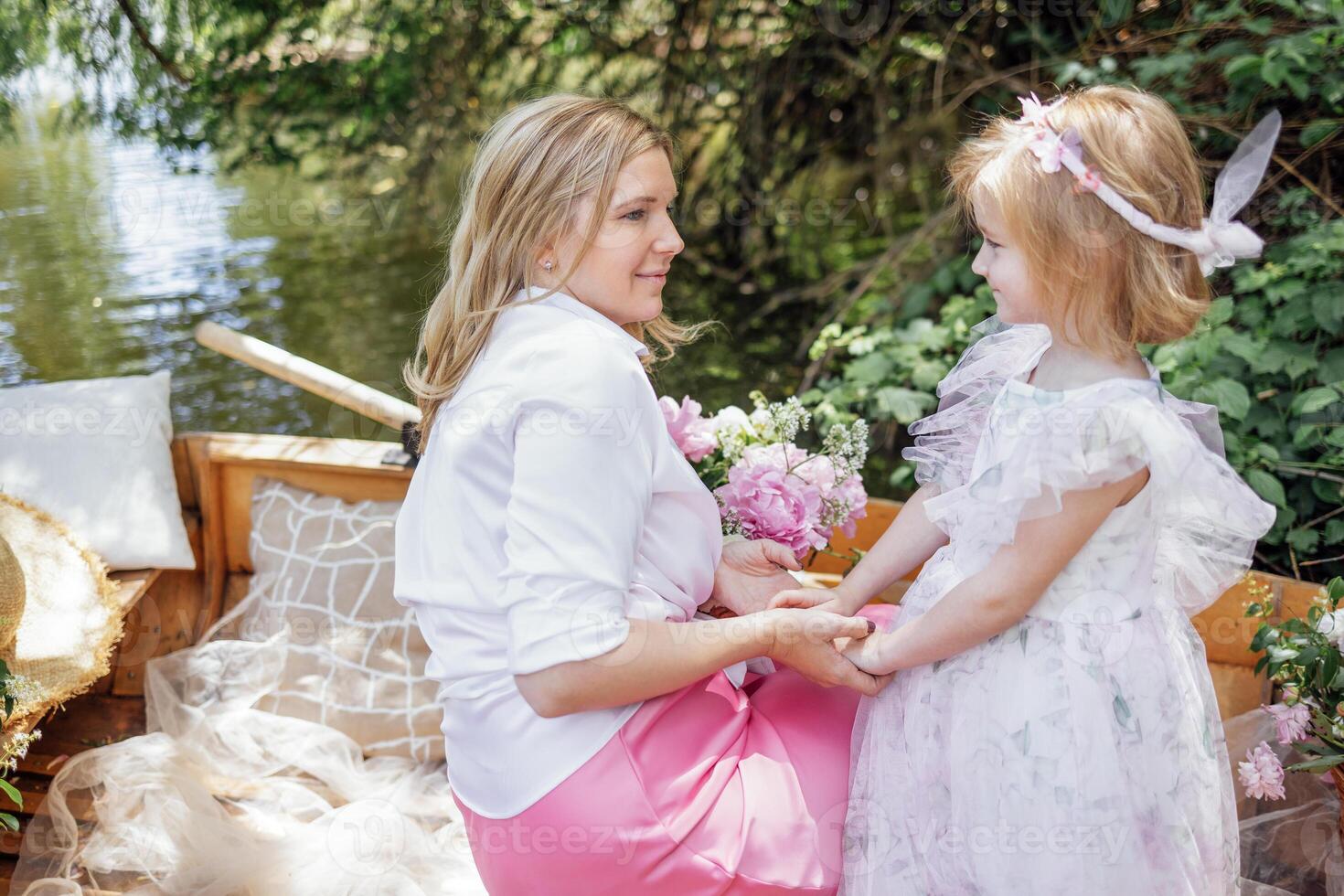Sweet blonde girl having fun with her adorable mom outdoors photo