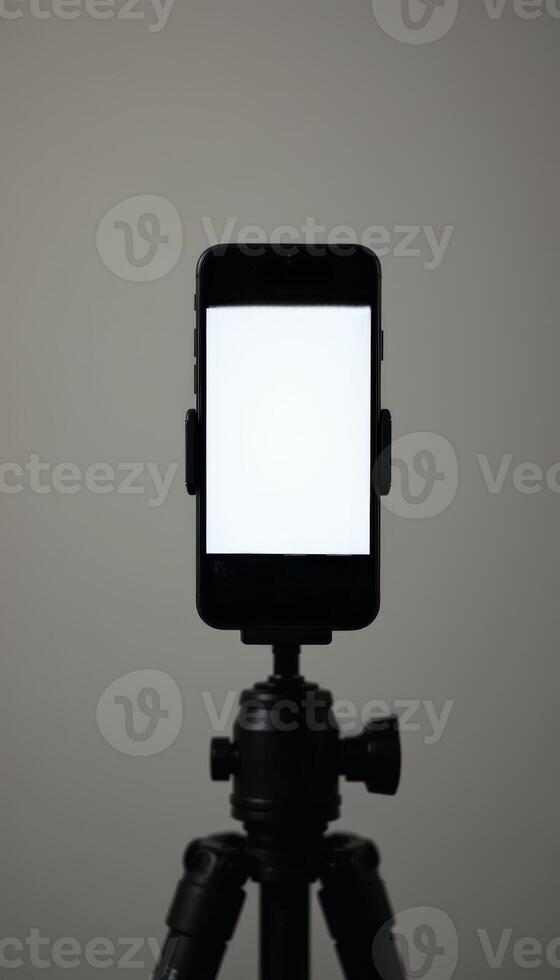 A smartphone secured on a tripod with a white screen, designed for content creation and streaming, ideal for mobile photography or vlogging setups. photo