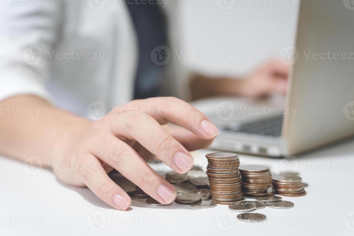 Person Stacks Coins While Using Laptop photo