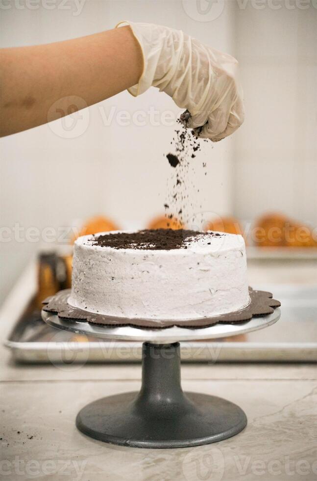 Man Spreading Oreo Crumb to the Top of Milles Crepes Cakes photo