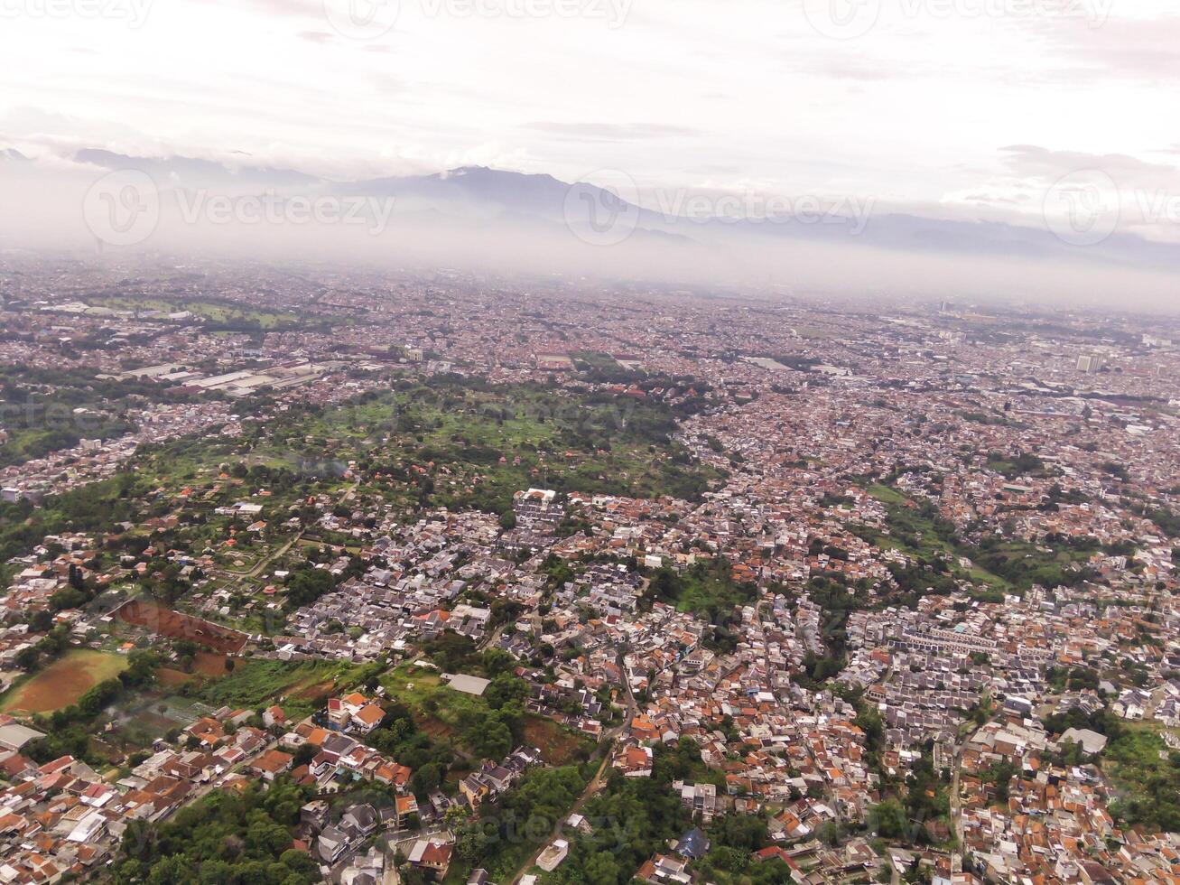 Aerial view of Residential District and Neighborhood in foggy morning. Suburbs of Bandung in West Java, Indonesia, photographed from above. Wide angle panoramic photo suitable for web banners