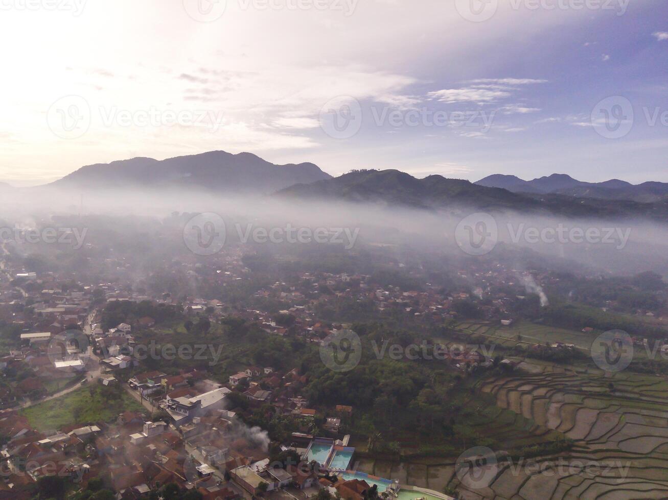 Bandung, Indonesia. Aerial Landscape view of foggy sky above mountains at dawn. High angle view of Mountain and cityscape in valley. Panorama of Highland in Bandung. Asia photo