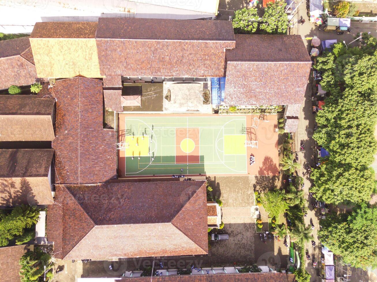 Aerial view of a soccer field in the middle of a brown-roofed building. Drone Landscape of an elite school, photographed from above. Wide angle panoramic photo