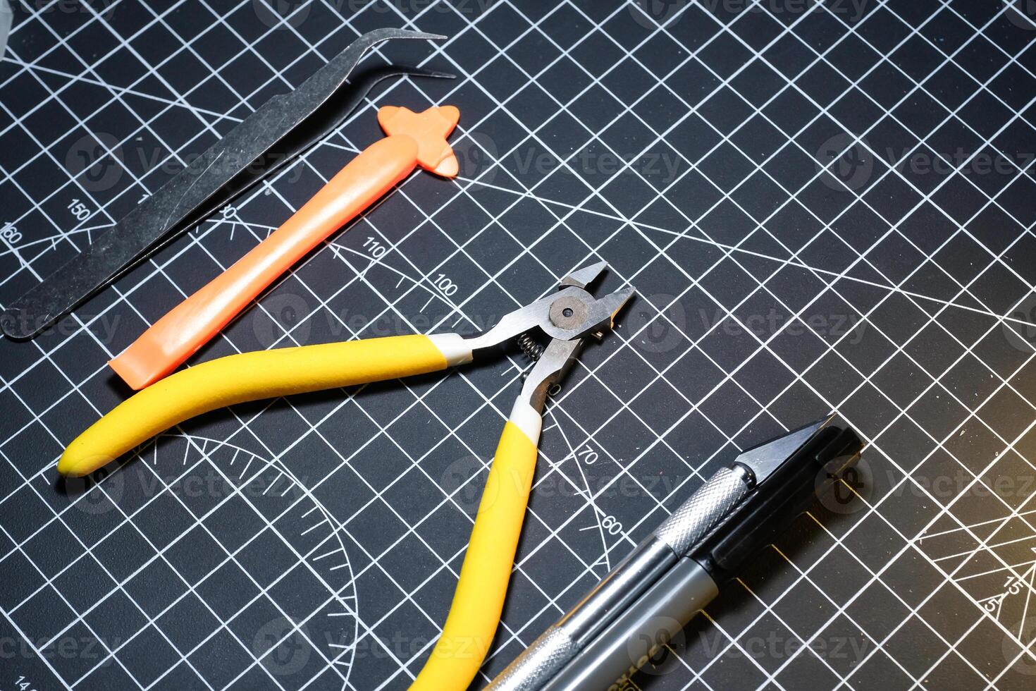 Tools set for building plastic model kits. Consisting of Nipper, Ink pen, cutting blade, plastic separator, and metal tweezer. Tools and equipment on black cutting mat. Toys and Model kits hobbies. photo