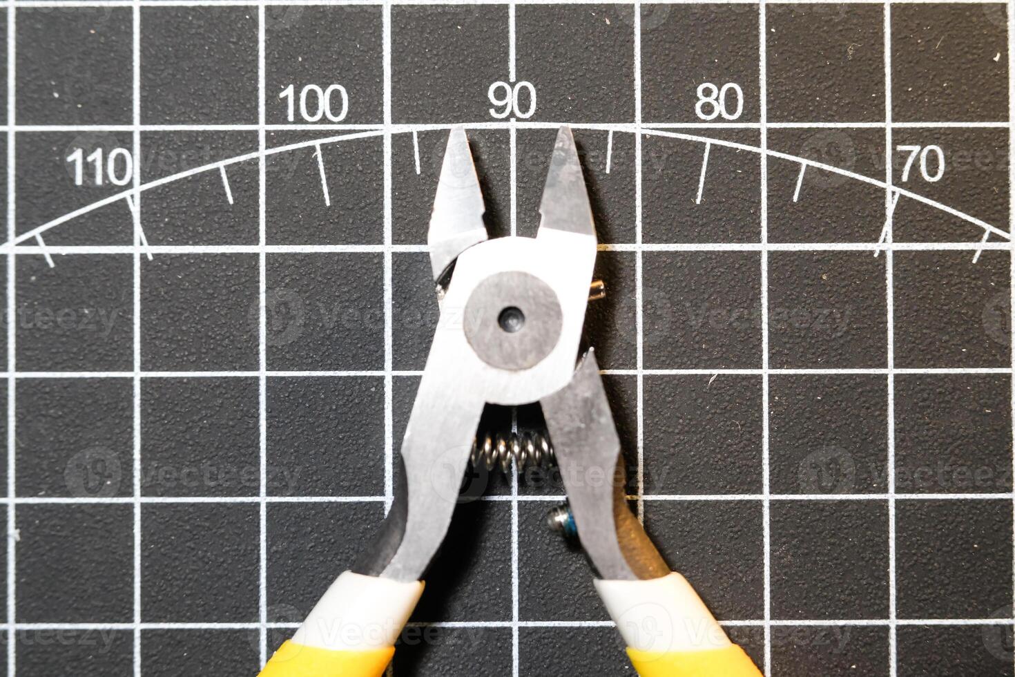 Metal nipper with yellow handle. Nipper Isolated on black striped cutting mat. Special cutting tool for plastic model kit hobby. Sharp pliers. Smooth and precision cutting. Negative Space photo
