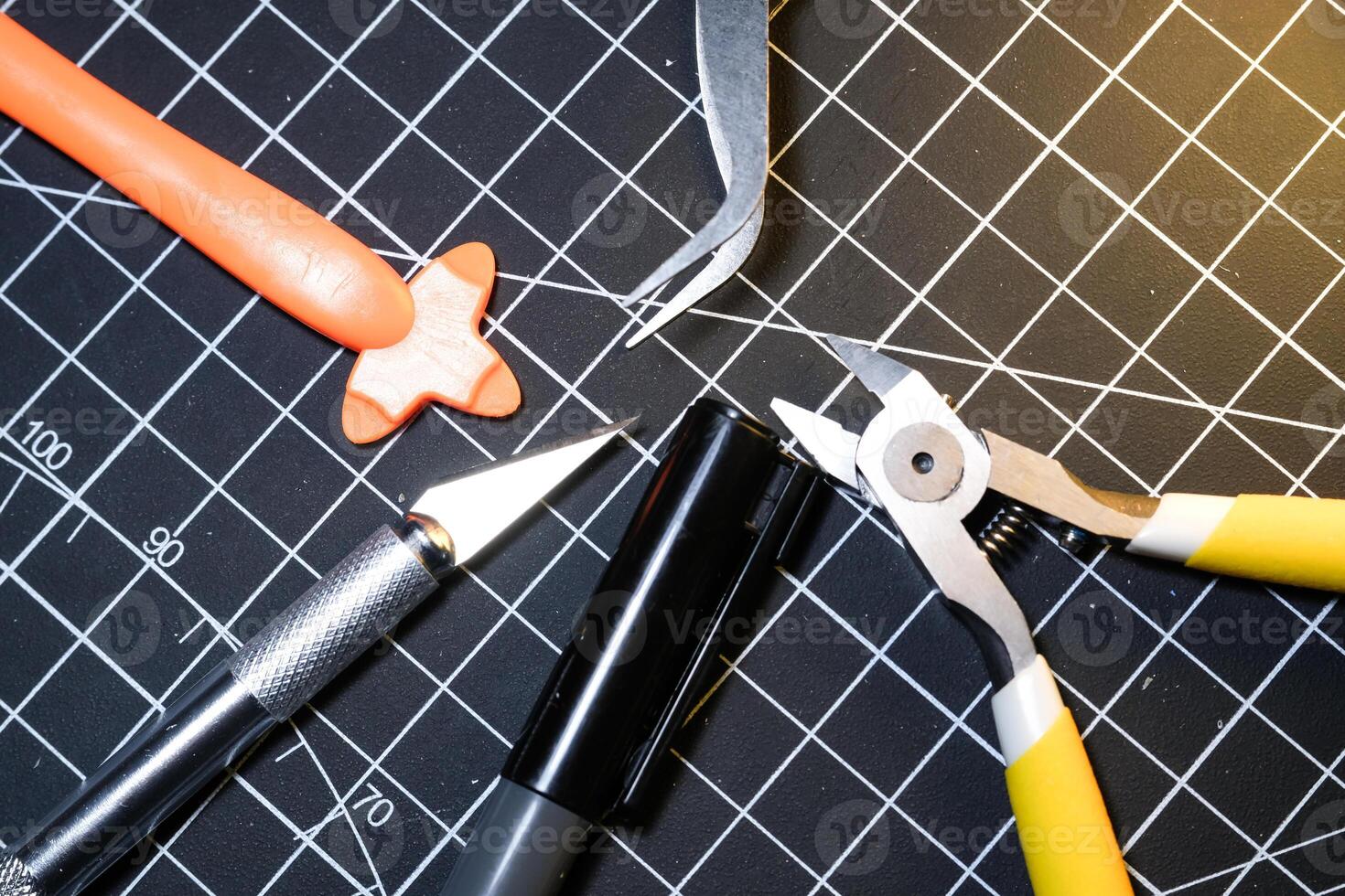 Tools for building plastic model kits. Consisting of Nipper, Ink pen, cutting blade, plastic separator, and metal tweezer. Tools and equipment on black cutting mat. Toys and Model kits hobbies. photo